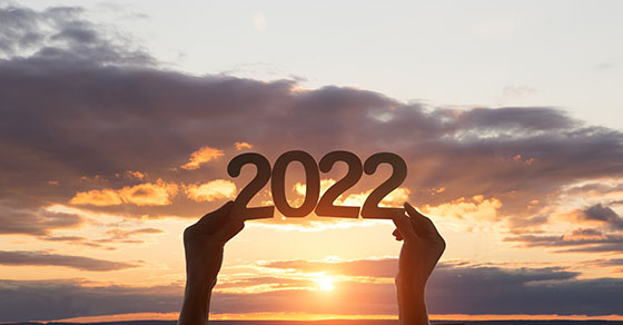 Person holding up a 2022 sign while the sun sets in the background.