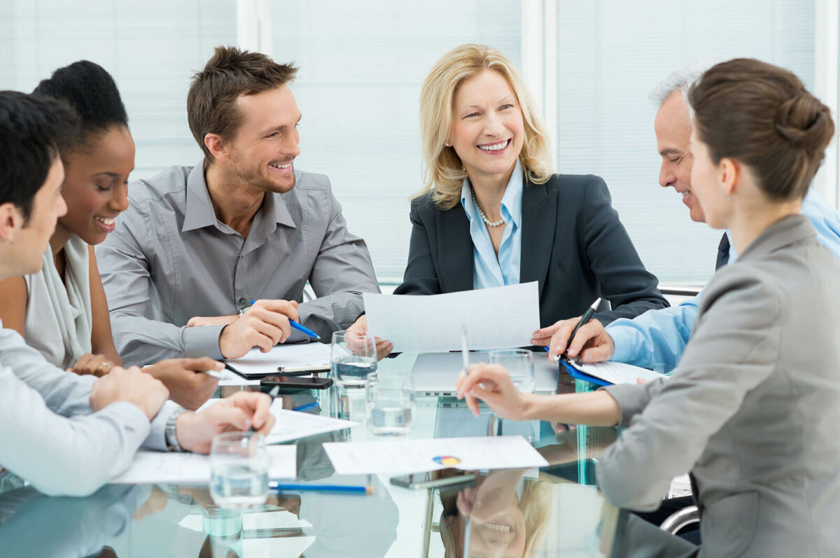 Group of business professionals discussing documents at a table and smiling.
