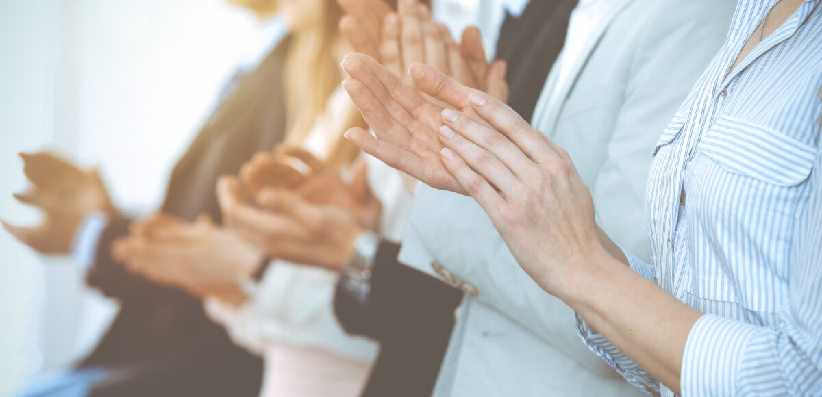 Business professionals in a row, clapping.